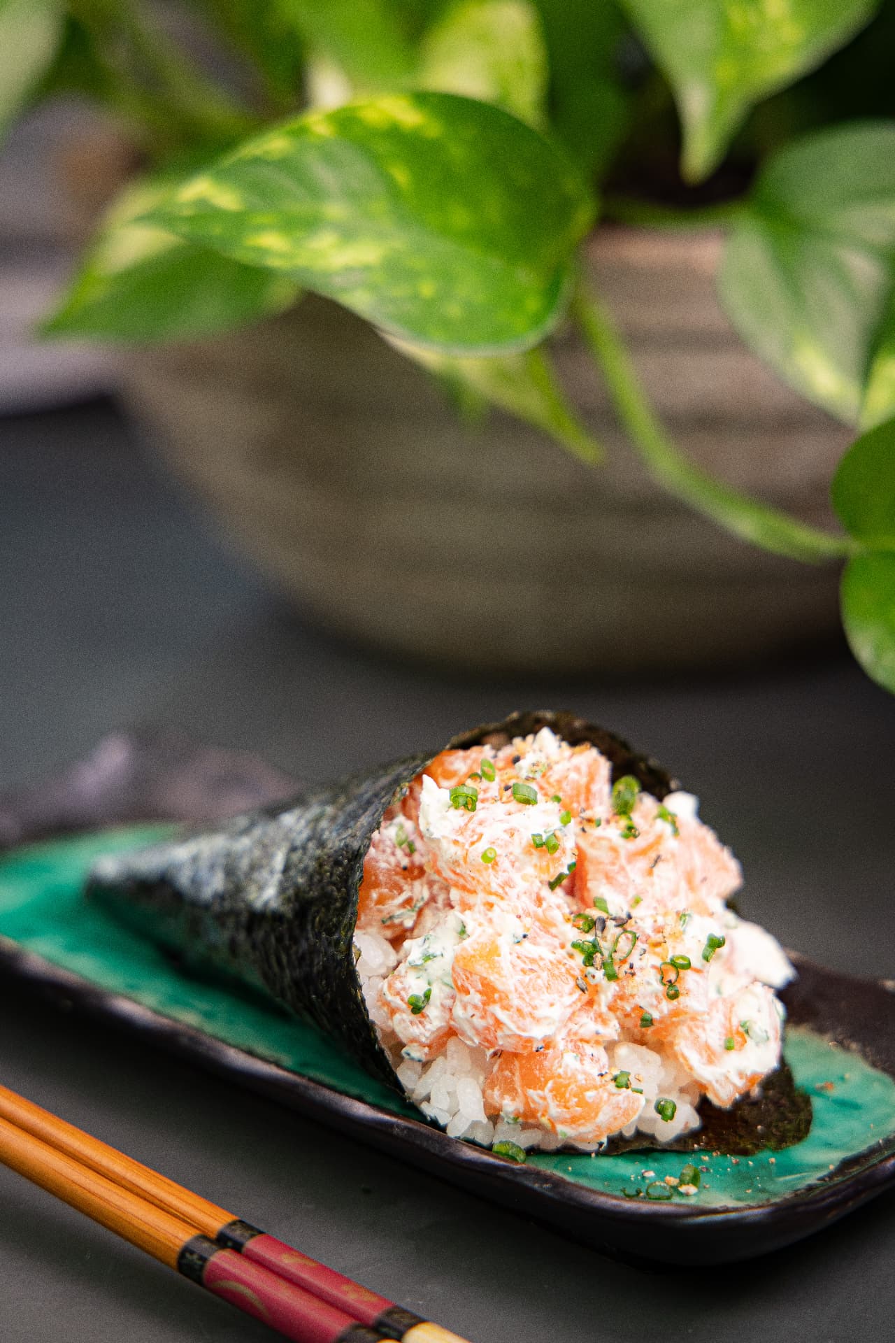 Temaki de salmão com cream cheese e cebolinha sobre arroz japonês em prato de cerâmica esmaltada
